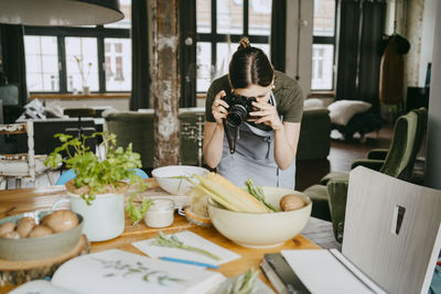 Food stylist photographing using digital camera in studio