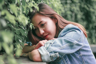 Portrait of young woman against plants