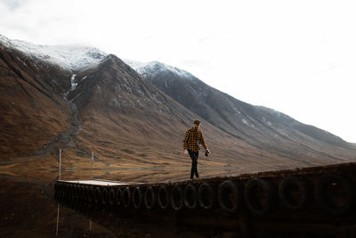 Rear view of person on snowcapped mountain against sky