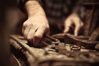 Midsection of male shoemaker with tools in workshop