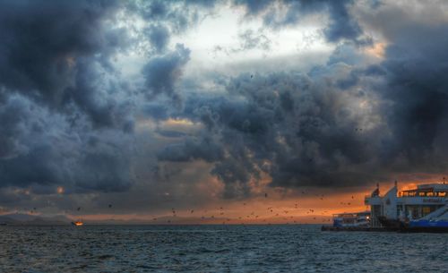 Ship sailing in sea against cloudy sky at dusk