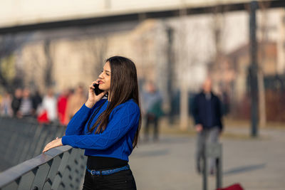 Teen girl talking on mobile smart phone outside by day