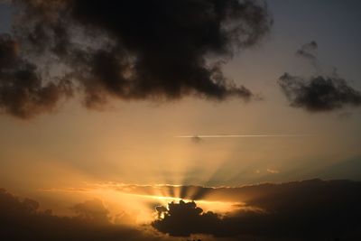 Low angle view of vapor trails in sky during sunset