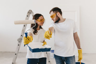 Happy smiling married couple engaged in renovation repair in the room of the house preparing to move