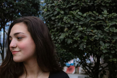 Portrait of smiling young woman against plants