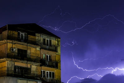 Low angle view of lightning over illuminated buildings at night