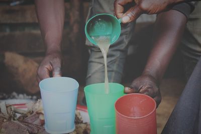 Cropped hand pouring drink in cup