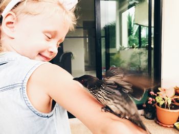 Bird perching on cute girl hand