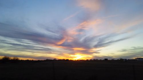 Scenic view of dramatic sky over field during sunset