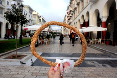 Woman holding a greek bagel on footpath in city of thessaloniki.