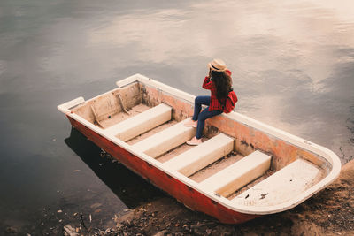 Young woman sitting on boat moored in lake