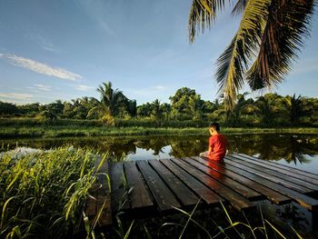  sitting by lake against sky