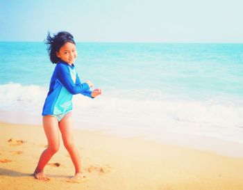 Portrait of girl in swimwear standing on beach against sky