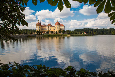 Church by lake against cloudy sky