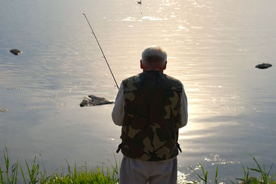 Rear view of man fishing in lake