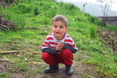 Portrait of smiling boy sitting on land