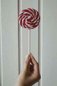 Cropped image of hand holding candy against door