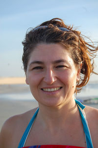 Portrait of smiling woman at beach against sky