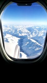 Aerial view of snowcapped mountains seen through airplane window