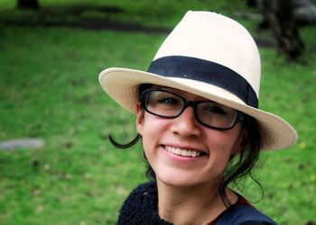 Portrait of smiling young woman wearing eyeglasses and hat at public park