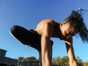 Low angle view of man against blue sky on sunny day