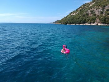 Woman swimming with pink inflatable ring in sea during sunny day