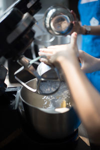 Cropped image of woman pouring flour in mixing bowl
