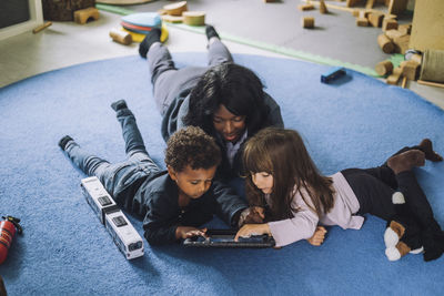 Female teacher using digital tablet with students in day care center