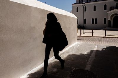 Rear view of woman standing against building wall