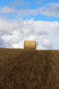 Hay bales on field against sky