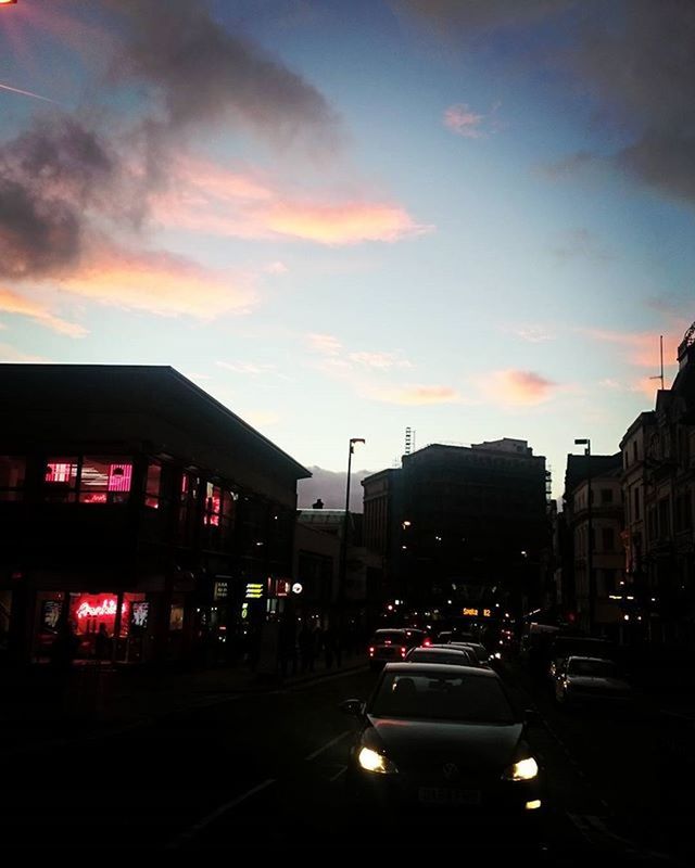 building exterior, architecture, car, built structure, sunset, transportation, land vehicle, city, sky, mode of transport, street, illuminated, traffic, road, cloud - sky, dusk, city life, city street, street light, building