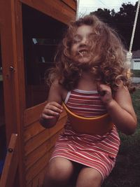 Cheerful girl enjoying swing at back yard