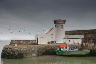 View of lighthouse by sea against buildings