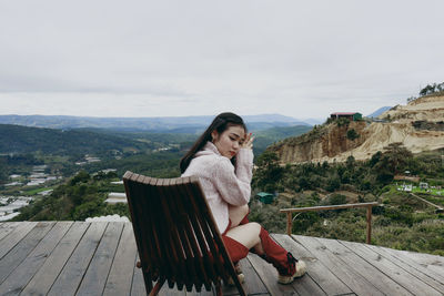 Side view of young woman standing against mountain