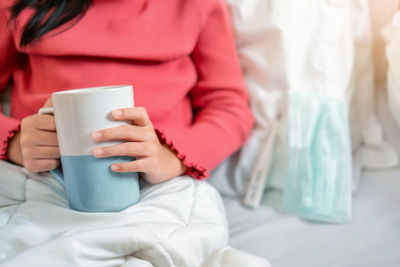 Midsection of woman holding coffee cup
