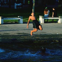 Full length of shirtless man jumping in water