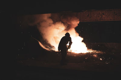 Silhouette of man with fire crackers at night