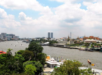 High angle view of buildings by river against sky