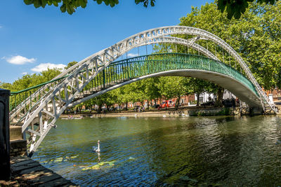 Arch bridge over river in city against sky