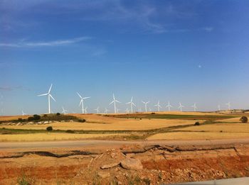 Wind turbines on field against blue sky