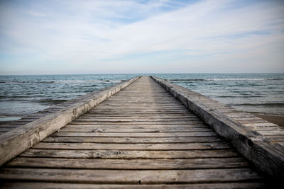 Surface level of wooden pier over sea against sky
