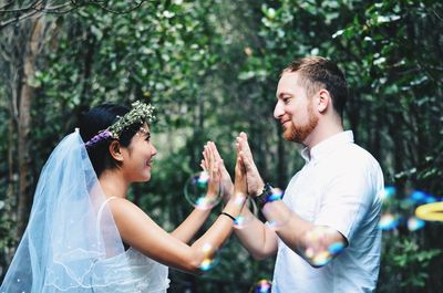 Side view of young couple standing against plants