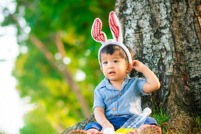 Portrait of cute boy looking away against trees