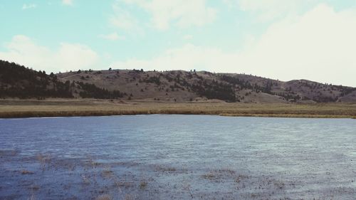 Scenic view of lake against cloudy sky