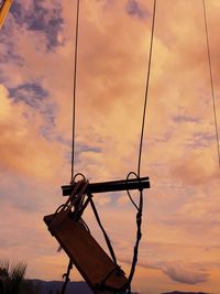 Low angle view of silhouette rope against orange sky