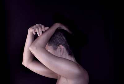 Midsection of shirtless man against black background