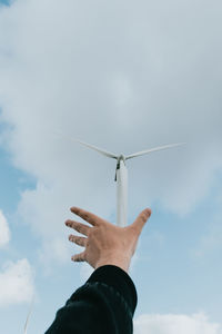 Low angle view of hand against blue sky