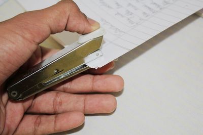 Cropped hand of person punching papers with stapler