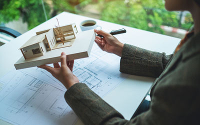 Midsection of architect holding model house