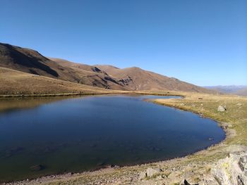 Scenic view of lake and mountains against clear blue sky